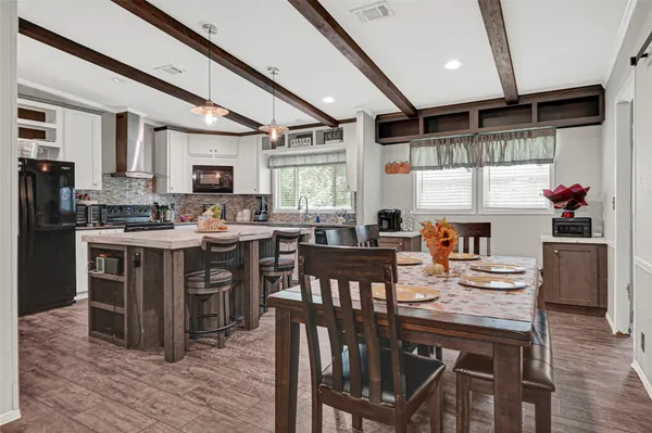 a kitchen with stainless steel appliances kitchen island granite countertop a table chairs and a refrigerator