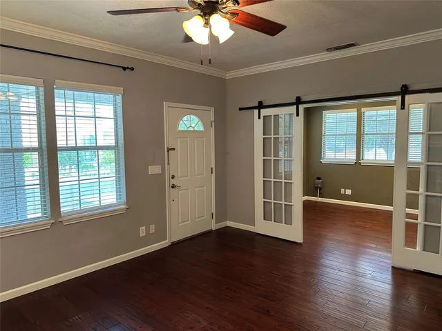 a view of an empty room with wooden floor and a window