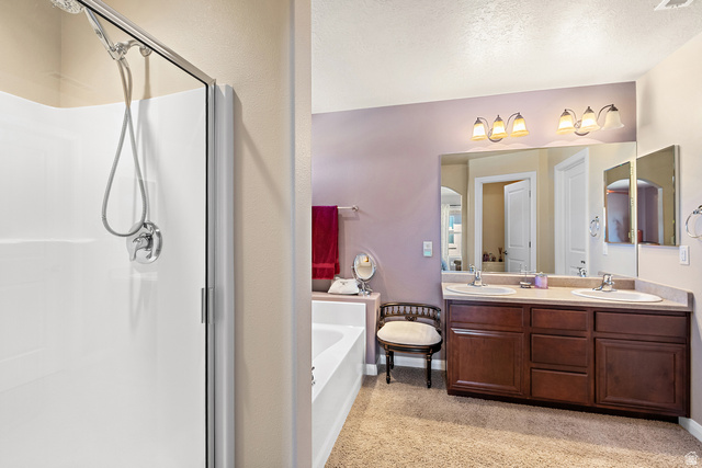 2484 Manzoni Road Santa Clara, UT 84765 - Photo 19 of 27 Bathroom with double vanity, a garden tub, a stall shower, and a textured ceiling