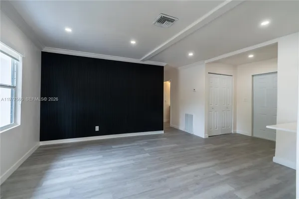 a view of an empty room with wooden floor and windows