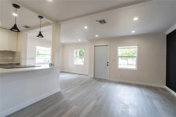 a view of an empty room with a window and wooden floor