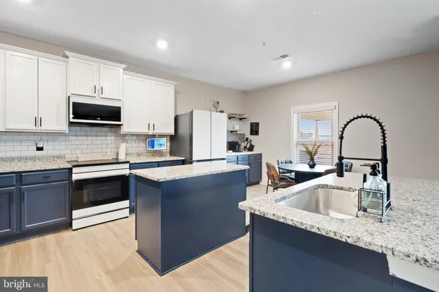 a kitchen with granite countertop a sink and a stove top oven with wooden floor