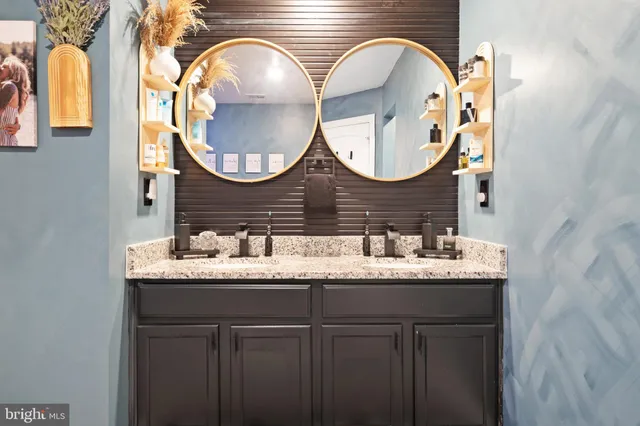 a bathroom with a granite countertop double vanity and a mirror