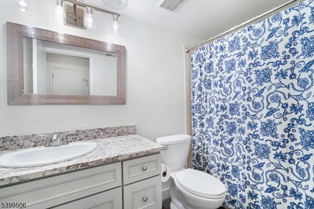 a bathroom with a granite countertop sink a toilet and a mirror