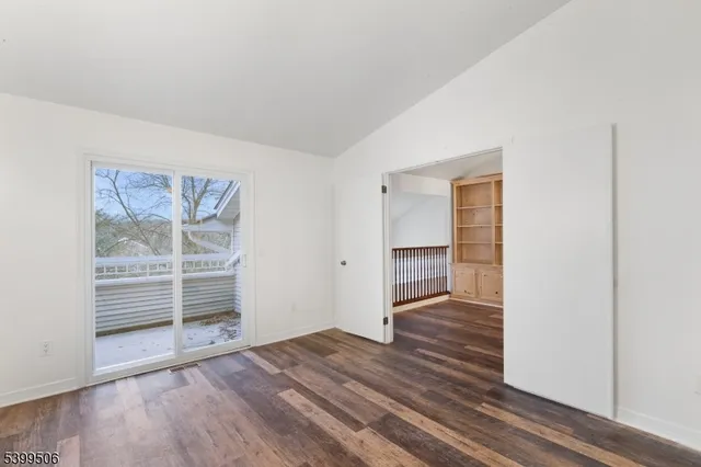 an empty room with wooden floor closet and windows