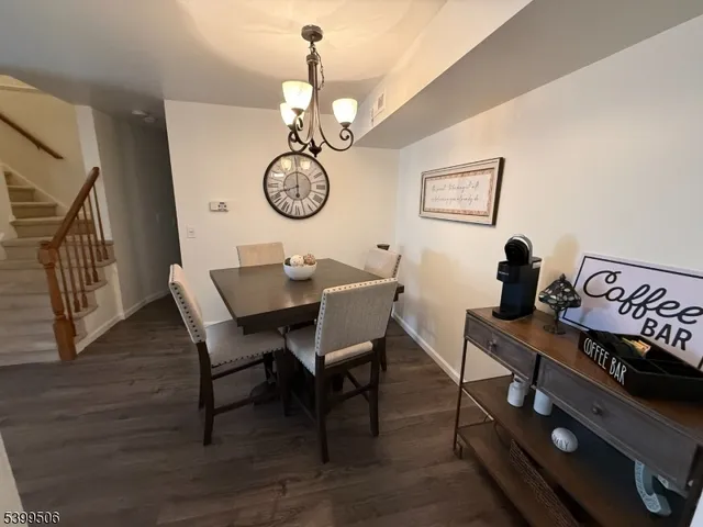 a view of a dining room and livingroom with furniture wooden floor a rug and a chandelier