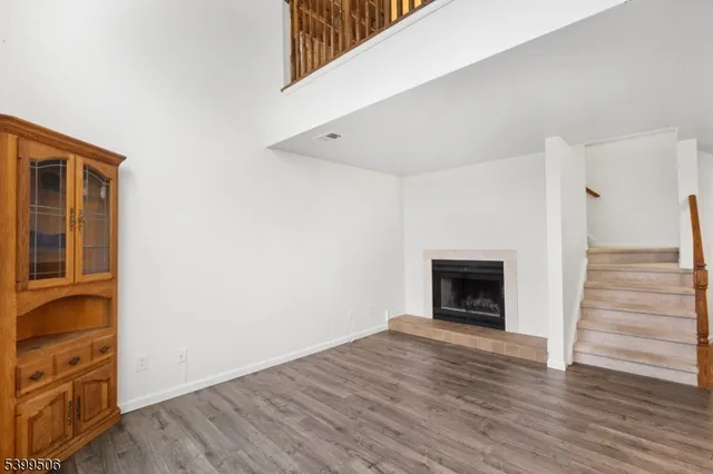 a view of an empty room with wooden floor fireplace and a window