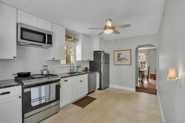 a kitchen with stainless steel appliances granite countertop a stove top oven a sink dishwasher and a refrigerator with wooden floor