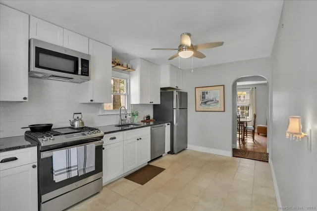 a kitchen with stainless steel appliances granite countertop a stove top oven a sink dishwasher and a refrigerator with wooden floor