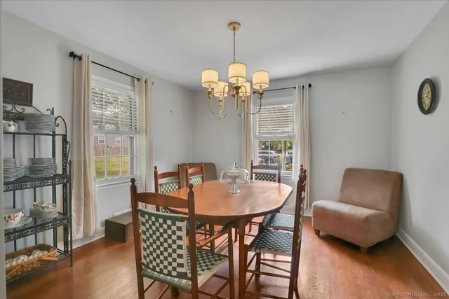 a dining room with wooden floor a chandelier a glass table and chairs