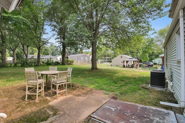 a view of a patio with table and chairs potted plants and large tree