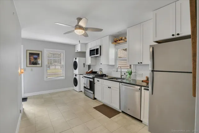 a kitchen with granite countertop a refrigerator a sink a stove and white cabinets