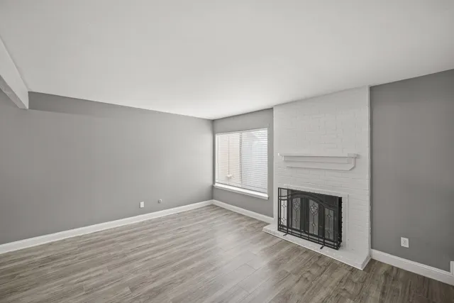 a view of empty room with wooden floor and fireplace
