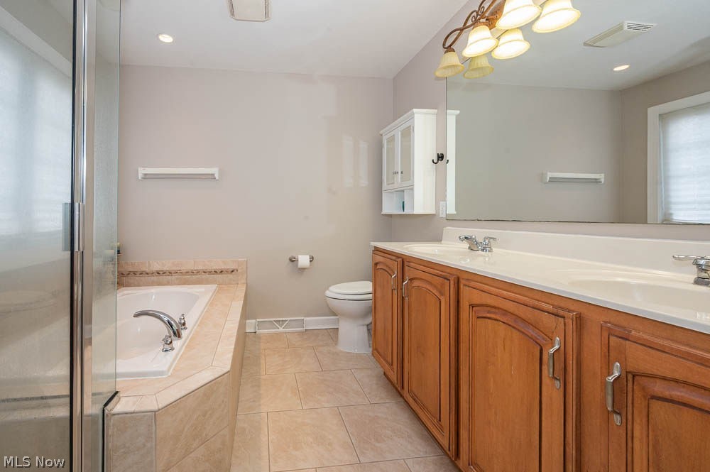 6787 South Palmyra Road Canfield, OH 44406 - Photo 14 of 30 Bathroom featuring a dual vanity with wood cabinetry and a white countertop, an integrated soaking tub, a glass-enclosed shower, tiled flooring, and neutral wall tones