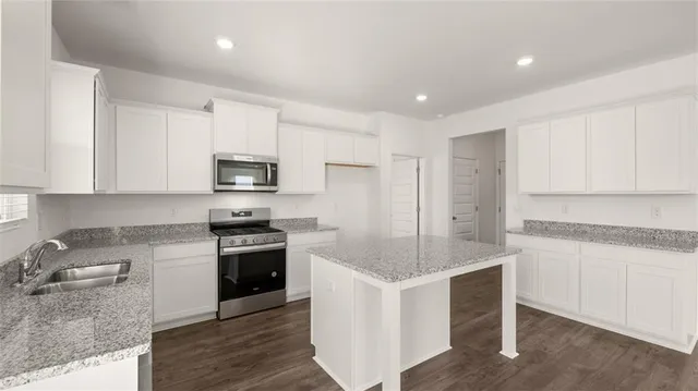 a kitchen with granite countertop white cabinets and stainless steel appliances