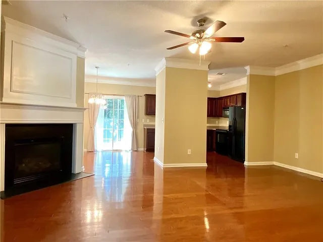 a view of an empty room with kitchen and fireplace
