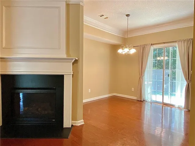 a view of an empty room with glass door and wooden floor