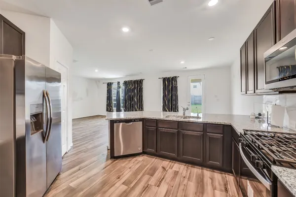 a view of a kitchen with a sink and dishwasher with wooden floor