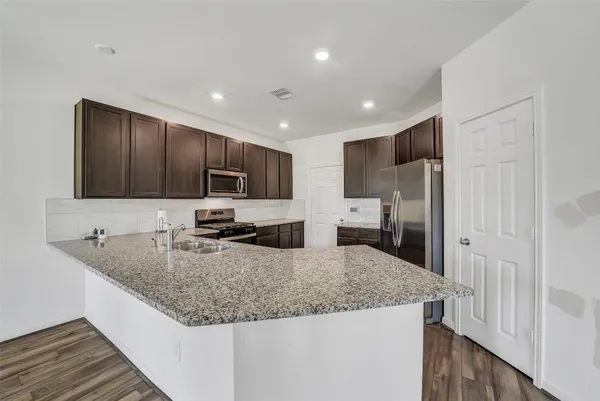 a kitchen with granite countertop kitchen island a sink stainless steel appliances and cabinets
