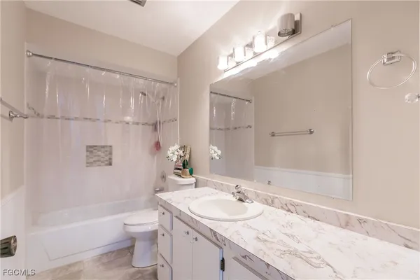 a bathroom with a granite countertop sink a toilet and shower