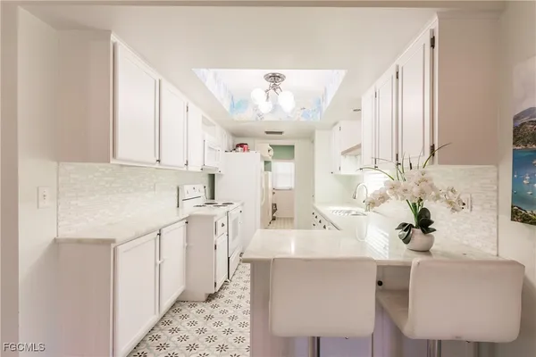 a living room with stainless steel appliances kitchen island furniture and a chandelier