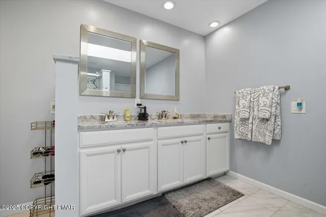 a bathroom with a granite countertop double vanity sink and a mirror