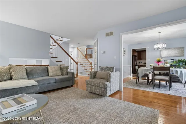 a living room with furniture and a dining table with wooden floor