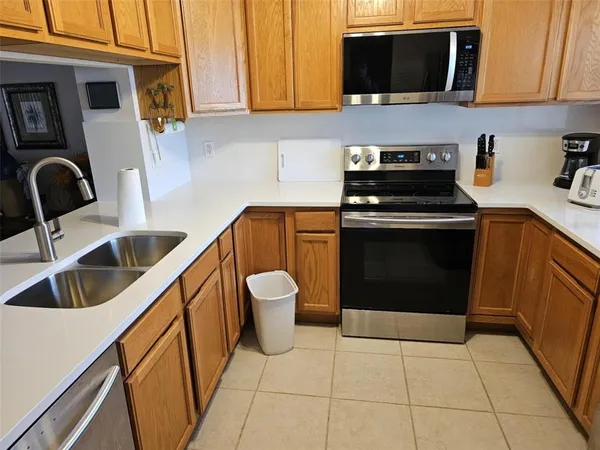 a kitchen with stainless steel appliances a stove a microwave a sink a refrigerator and cabinets