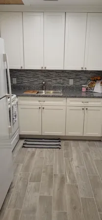 a kitchen with stainless steel appliances white cabinets and wooden floor