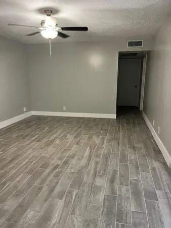 an empty room with wooden floor chandelier and windows
