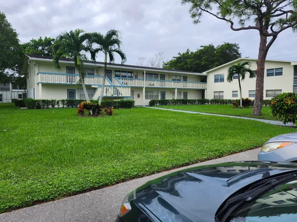 a view of a house with a big yard and palm trees
