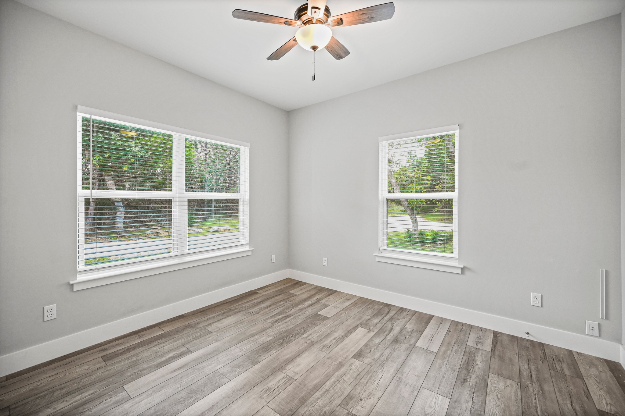 231 North Rainbow Ranch Road Wimberley, TX 78676 - Photo 22 of 40 A quiet bedroom showcases light wood-look flooring and multiple windows, providing a calm retreat.