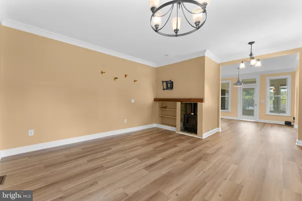 a view of an empty room with window and wooden floor