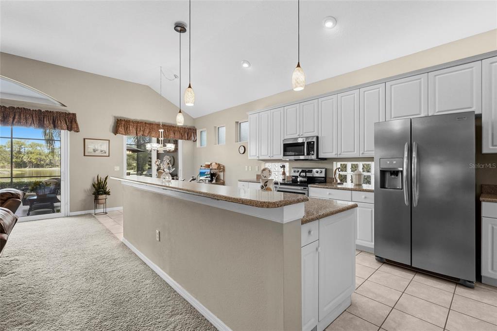 7822 Troon Court Lakewood Ranch, FL 34202 - Photo 4 of 83 a kitchen with stainless steel appliances granite countertop a refrigerator a stove a sink a dining table and chairs with white cabinets