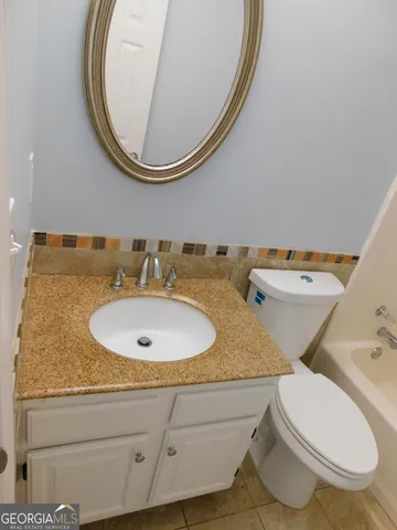 a bathroom with a granite countertop toilet and a sink