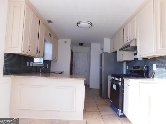 a kitchen with stainless steel appliances granite countertop a refrigerator sink stove and cabinets