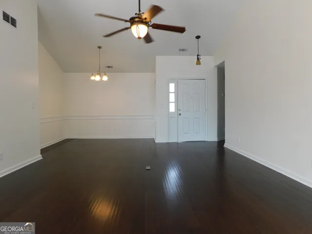 an empty room with wooden floor and fan