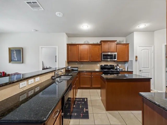 a kitchen with stainless steel appliances granite countertop a sink a stove top oven a counter space and cabinets
