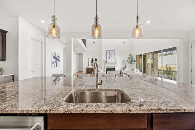 a kitchen with granite countertop a sink a counter top space and living room view