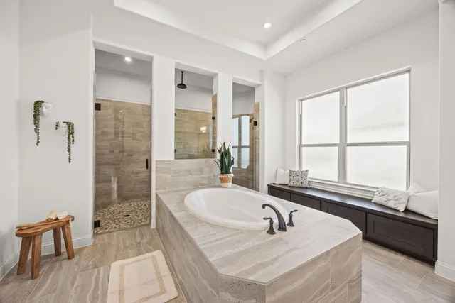 a bathroom with a tub a sink and a large mirror