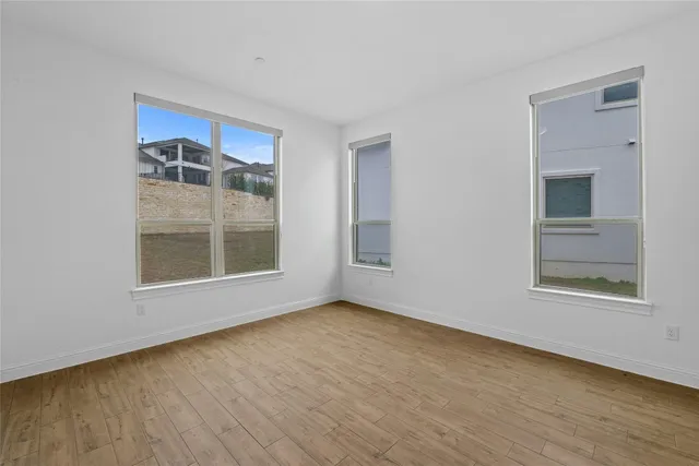 a view of an empty room with a window and wooden floor