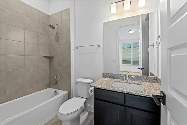 a bathroom with a granite countertop sink toilet a large mirror a shower and a bathtub
