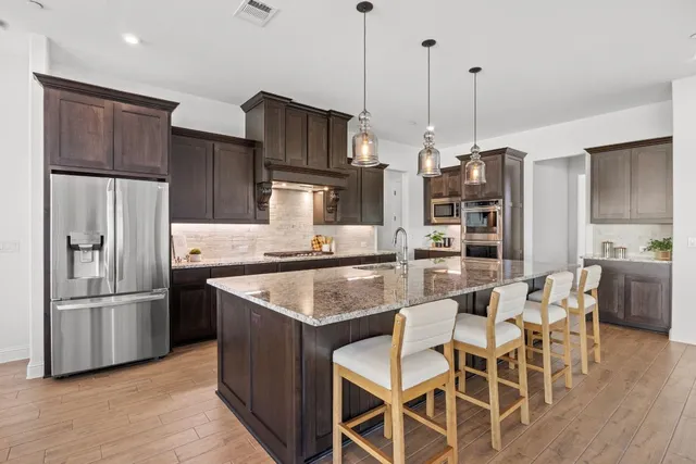 a kitchen with stainless steel appliances granite countertop a sink a refrigerator and a stove