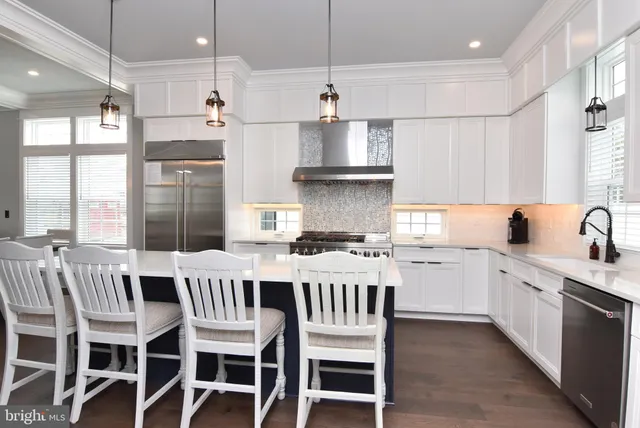 a kitchen with stainless steel appliances granite countertop a sink a stove a refrigerator dining table and chairs