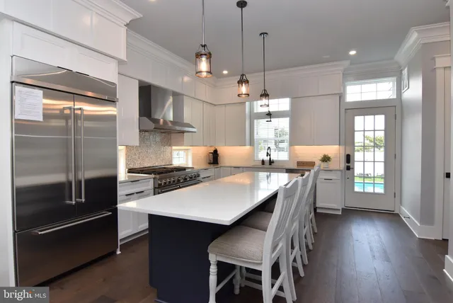 a kitchen with stainless steel appliances granite countertop a stove a refrigerator a sink a dining table and chairs with wooden floor