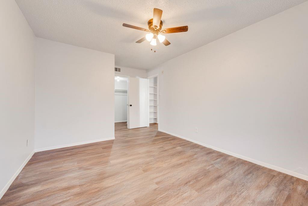 5514 Boca Raton Boulevard, Unit 438 Fort Worth, TX 76112 - Photo 16 of 25 a view of an empty room with chandelier fan and wooden floor