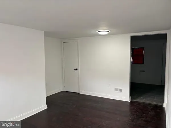 a view of an empty room with wooden floor and closet