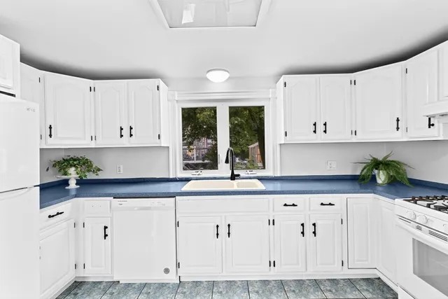 a kitchen with granite countertop white cabinets and white appliances