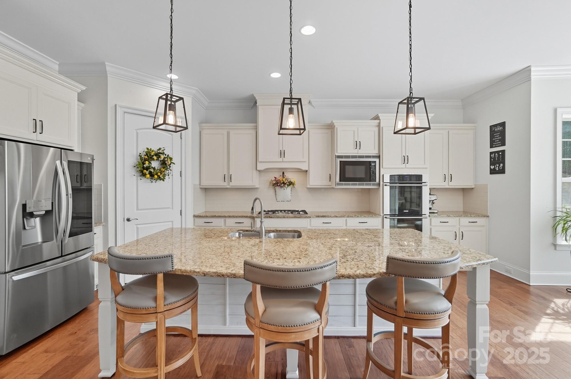 546 Abelia Lane Fort Mill, SC 29708 - Photo 17 of 43 a kitchen with stainless steel appliances kitchen island granite countertop a dining table chairs and white cabinets
