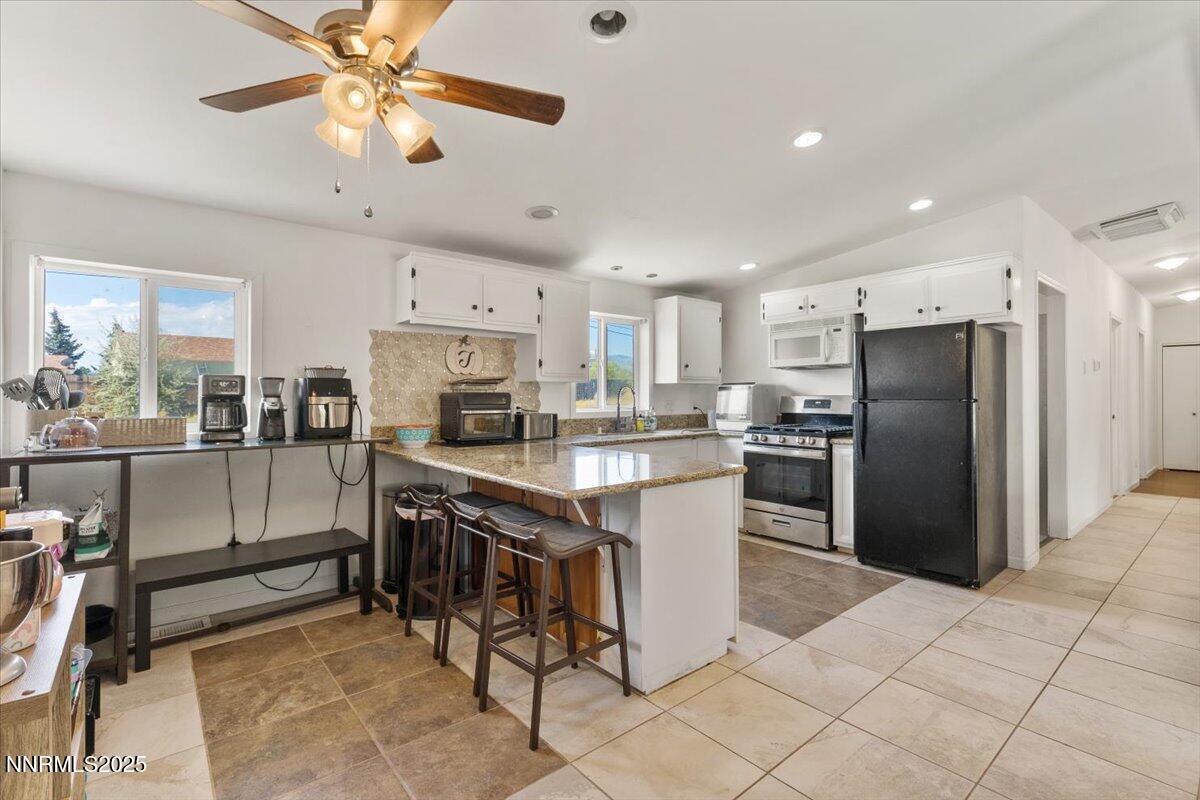 17570 Thrush Lane Reno, NV 89508 - Photo 12 of 30 a kitchen with stainless steel appliances kitchen island granite countertop a refrigerator a stove a sink a dining table and chairs